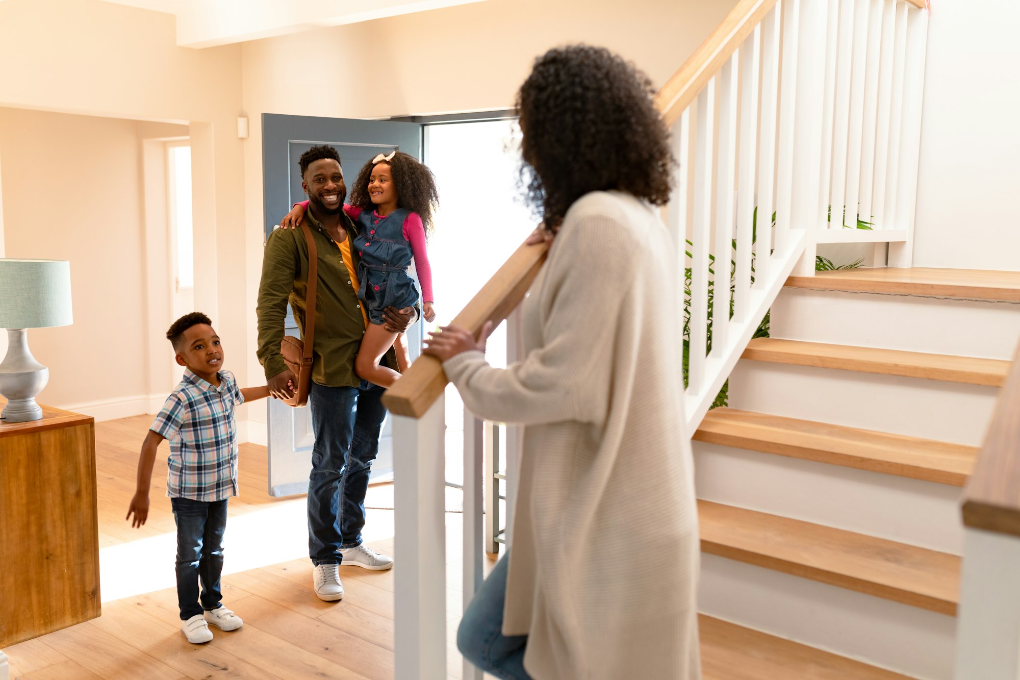 Happy african american family welcoming father coming back home